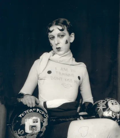 Claude Cahun, autorretrato de 1927 con la frase I am in training, don’t kiss me escrita en la polera